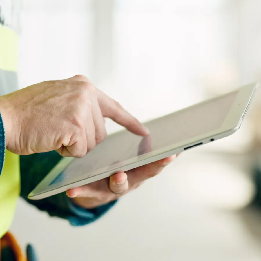 Contractor in a hi-vis vest checking a tablet on a job site